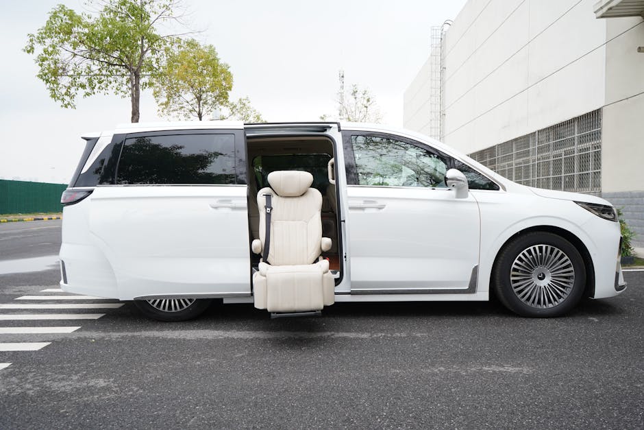 White minivan with automatic sliding door and retractable seat on a city street during daytime.